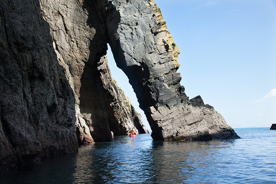 David Horkan sea kayaking through a sea arch